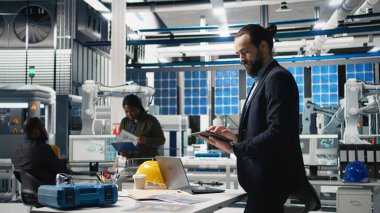 Genel müdür, temiz enerji endüstrisi ekipmanlarıyla modern üretim hattını sembolize eden bir güneş paneli imalat tesisinde teftiş yapıyor. Sürdürülebilir çözümler. Kamera A.