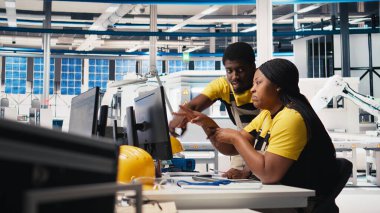 Yüksek teknolojili bir güneş paneli fabrikasında çalışan siyah mühendislik ekibi, dinlenme süresini ve kusursuz üretim sürecini azaltıyor. Teknisyenler güneş enerjisi üretimini optimize ediyorlar. Kamera B.