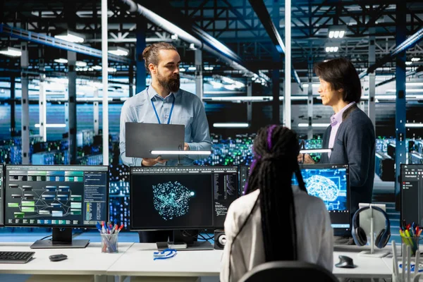 Yüksek teknoloji veri merkezinde beyin fırtınası yapan mühendisler, AI model parametrelerini sistemleri güncellemek için ayarlıyorlar. Sunucu odası çalışanları ekipman süper bilgisayar donanımları için derin öğrenim kontrolü programlıyorlar