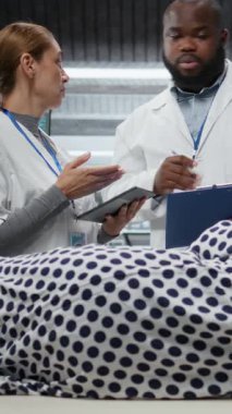 Dikey Video Çeşitli sağlık çalışanları bir ilaç denemesi sırasında bir hastayı muayene ediyor, tedavi sonuçlarını, yan etkilerini ve dozaj tepkilerini izliyor. Gelişmekte olan tıp ve sağlık yeniliği. Kamera A.