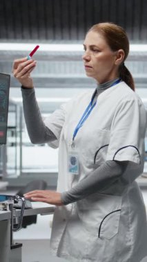 Dikey Video Araştırmacısı kan örneklerini inceliyor ve klinik bir deney için hastayı gözlem altında tutuyor, ilaç dozajını değerlendiriyor ve reaksiyonları inceliyor. Tıbbi keşifte ilerleme var. Kamera A.