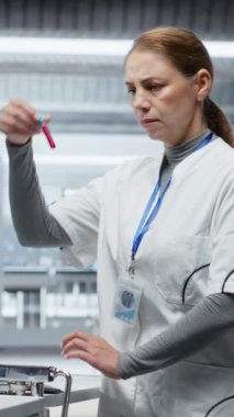 Dikey Video Araştırmacısı kan örneklerini inceliyor ve klinik bir deney için hastayı gözlem altında tutuyor, ilaç dozajını değerlendiriyor ve reaksiyonları inceliyor. Tıbbi keşifte ilerleme var. Kamera B.