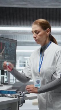 Dikey Video Bilimadamı modern laboratuvar ortamında test tüplerini kanla inceliyor, yeni bir ilaç test ediyor ve yan etkilerini kaydediyor. Güvenlik ve etkinliği sağlamak için dozaj tepkisi analiz ediliyor