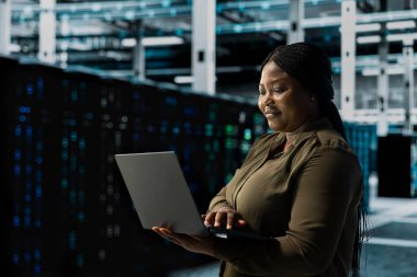 Gülümseyen mühendis veri merkezinin elektronik verilerini inceliyor. Happy sunucu merkezi bilişim uzmanı bulut depolama şirketlerinin kullandığı ekipmanları korumak için yedekleme yapıyor