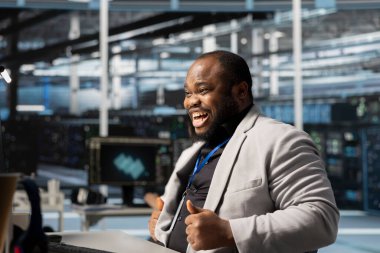 Sunucu merkezindeki aşırı neşeli programcı sistem verimliliği ölçümlerinin geliştirilmesinden memnun. Veri merkezinde çalışan kendinden geçmiş Afrikalı Amerikalı adam gelişmiş ağ altyapı performansından memnun.