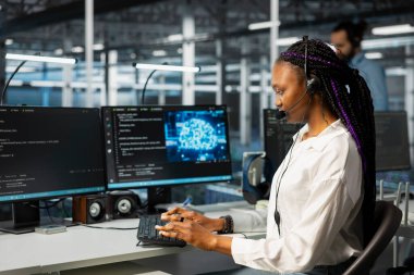 Veri merkezindeki yazılım geliştiricisi kulaklık mikrofonuyla konuşuyor, kullanıcı teknolojisi desteği sağlamak için yapay zekayı kullanıyor. Uzaktan arama sırasında makine öğrenme teknolojisi kullanan istemcilere yardımcı olan sunucu odasında bilişim uzmanı