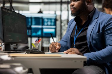 Erkek genel müdür, bir not defterine notlarla proje planlaması yapar ve çevrimiçi tahminlerden veri çıkarır. Organizasyon başarısı ve daha fazla sermaye fonu elde etme konusunda uzman.