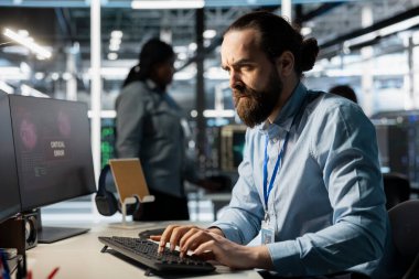 Sunucu odasındaki kaşlarını çatan programcı, PC 'deki kritik donanım hatasını gösteren tanı raporunu okuduktan sonra endişeli. Sistem güncellemelerinden rahatsız olan çalışan uyarı uyarıları