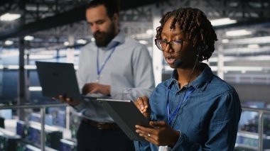Sunucu odası yönetimi, altyapı teknik desteği sağlamak için tablet ve kulaklık mikrofonu kullanıyor. Veri merkezi bilişim uzmanı uzak ekiplerle koordine ederken arka uç sorunlarını çözer