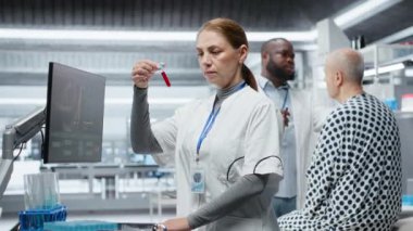 Bilim adamı modern laboratuvar ortamında test tüplerini kanla inceliyor, yeni bir ilacı test ediyor ve yan etkilerini kaydediyor. Güvenlik ve verimliliği sağlamak için dozaj tepkisi analiz ediliyor. Kamera B.