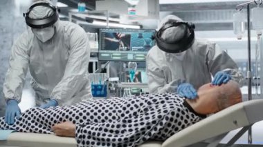 Tehlikeli madde giysileri içindeki doktorlar hastalıkların yayılmasını önlemek ve küresel sağlık hizmetlerini desteklemek için güvenli bir laboratuvarda enfeksiyon belirtileri gösteren hastaları muayene ediyorlar. Kamera B.