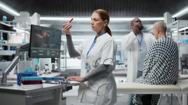 Araştırmacı kan örneklerini inceliyor ve klinik bir deney için hastayı gözlem altında tutuyor. İlaç dozajını değerlendiriyor ve reaksiyonları inceliyor. Tıbbi keşifte ilerleme var. Kamera A.