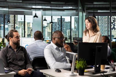 Çeşitli çalışanlar hedeflere ulaşmak için fikir ve fikir alışverişinde bulunuyor, ofisteki bilgisayar masasında rapor paylaşımı ve tahminlerde bulunuyor. Geliştirme için iş istihbaratını yöneten çalışma ekibi.