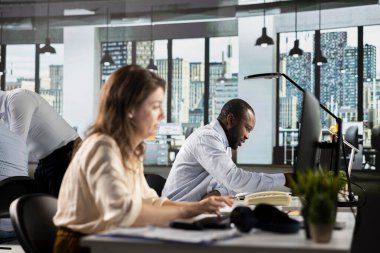 Profesyonel personel, iş toplantısı sırasında finans numaralarını ve şirket belgelerini analiz ediyor. Ekip raporlama, piyasa araştırması ve şirket geliştirme için kaynak tahsisini tartışır.