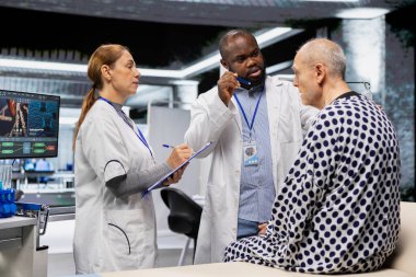 Tıbbi araştırmacılar, bir laboratuvar uyuşturucu araştırmasında bir hastanın klinik değerlendirmesini gerçekleştirmekte, tedavi güvenliği ve farmakoloji sonuçlarını test ederek sağlık hizmetlerindeki ilerlemeyi hızlandırmaktadır..