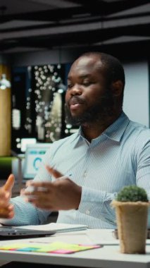 Dikey Video Afrikalı Amerikalı adam hissedarlarla web video konferansında el sallıyor, ofis masasından internetteki bir sohbete katılıyor. Çalışan ağları, yürütme kuruluyla görüşmeler