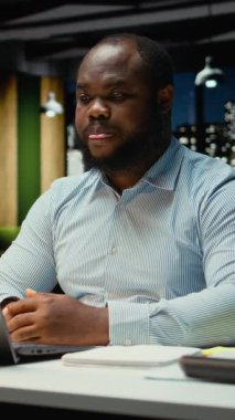 Dikey Video Siyah iş adamı karanlık ofisten çevrimiçi video görüşmesi yapıyor, web kamerasında göz teması kuruyor. Anlamlı konuşmalar için toplantıya katılmak, yatırımcılarla yakınlık kurmak