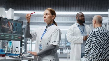 Kadın doktor, klinik deney sırasında hastadan alınan kan örneklerini kontrol ediyor. Hayati değerleri, dozaj reaksiyonlarını ve tedavi sürecini izliyor. Kadın ileri düzey sağlık bilimleri üzerine çalışıyor. Kamera B.