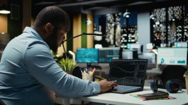 Öfkeli siyahi adam ön x eğilimi düşerken para kaybediyor, borsa göstergelerinin düştüğünü görüyor ve gece geç saatlerde iflastan endişe ediyor. Stresli insan.