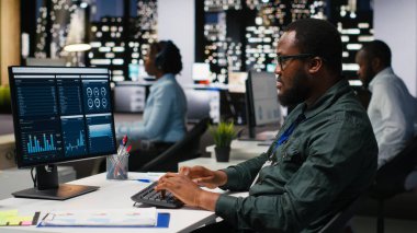 KPI ölçümlerini monitörde ve masaüstünde inceleyen ofis çalışanı, hedeflere ve başarıya ulaşmak için bir vizyon ve iş stratejisi oluşturmaktadır. Mesai sonrası profesyonel zihniyet.