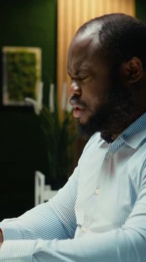 Dikey video, gece geç saatlerde zihinsel yorgunluk ve rahatsızlıkla boğuşan sorunlu personelin yoğun iş yükü ve sağlıksız yaşam tarzı belirtileri gösteriyor. Endişeden bunalmış bir adam. Kamera.