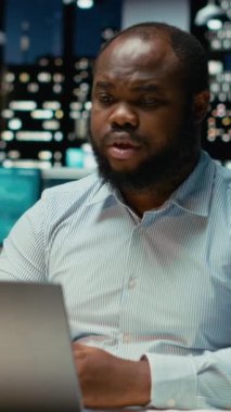 Dikey Video Siyah iş adamı karanlık ofisten çevrimiçi video görüşmesi yapıyor, web kamerasında göz teması kuruyor. Anlamlı konuşmalar için toplantıya katılmak, yatırımcılarla yakınlık kurmak