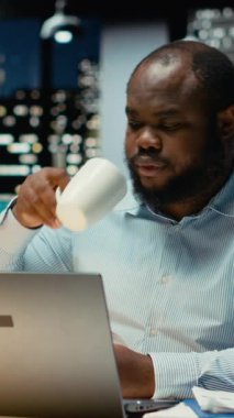 Bir kupadan kahve yudumlayan ve kapanış ofisini kuran dikey Afrikalı Amerikalı işçiler, geç saatlerin farkına varıyor ve ayrılma görevini tamamlıyor. Genç çalışanlar fazla mesaiden sonra evlerine dönüyorlar. Kamera.