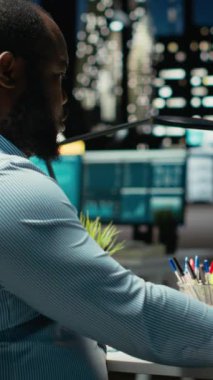 Dikey Video Erkek Ofisi çalışanı geceleri rakamları ve mali veri ölçümlerini kontrol ediyor, güncellemeleri belgeliyor ve yaklaşan iş etkinliklerinin gündemini düzenliyor. İdari görevler. Kamera B.