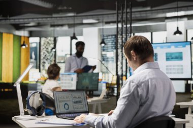 Beyaz erkek ofis çalışanı, gelecek raporlar için çevrimiçi belgeleri incelemeye ve veri yönetimiyle ilgilenmeye odaklanıyor. Kafkasyalı iş adamı şirket çalışma alanında dizüstü bilgisayarla çalışıyor..