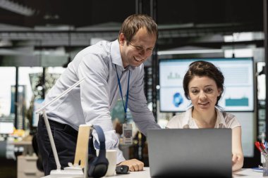 Modern çalışma alanındaki neşeli beyaz çalışanlar proje geliştirme ve iş analizlerini tartışıyorlar. Erkek ve kadın iş arkadaşları strateji, raporlar ve yatırım planları üzerinde etkili bir şekilde birlikte çalışırlar..