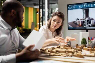 Çok ırklı müteahhitler ve müteahhitler şehir konut modelleri ve yaklaşan konut geliştirme projesinin planlarını tartışıyorlar. Akıllı şehir planlama oturumu.