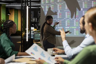 Projeksiyon tahtasında veri tahmin eğilimleri sunan takım lideri, bir gece toplantısında iş arkadaşlarıyla bilgi grafikleri verilerini paylaşıyor. Proje geliştirme planlamak için şirket etkinliği.