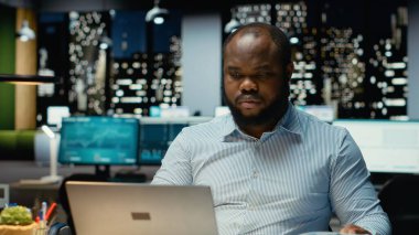 Erkek şirket analisti veri raporlarını okuyor ve dizüstü bilgisayardan kontrol ediyor, proje planlıyor ve mesai saatleri dışında görevler ayarlıyor. Hedef başarısı için not ve el yazısı.