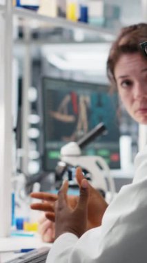 Laboratuvar kimya mühendislerinden oluşan dikey video ekibi saflık doğrulaması için cam şişelerdeki kimyasal çözeltiyi inceliyor. Takım çalışması labaratuar arkadaşları ayırıcı konteynırları hazırlayın