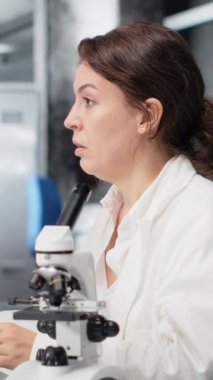 Dikey video yorucu laboratuvar moleküler biyoloğu bilgisayar masasında geriniyor, DNA hasta verilerini işliyor. Yorgun laboratuvar çalışanı gözlerini kapatıyor, rahatlamak için bilgisayardaki genetik analize ara veriyor.