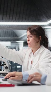 Dikey video kimya mühendisi, araştırma tesisinde mavi gösterge çözeltisiyle laboratuvar camları kullanıyor. Laboratuvarda kimyasal sıvı içeren silindiri inceleyen kimyager madde özelliklerini analiz ediyor.