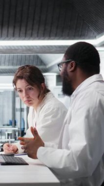 Dikey video laboratuarı kimyagerleri test tüpündeki sıvıları inceleyip klinik deneyler sırasında buluşlar arıyorlar. Araştırma tesisi çalışanları kimyasal tüpleri karşılaştırıp test ediyorlar.