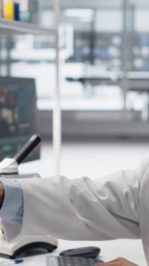 Üst düzey biyokimyacı laboratuvar camlarını sallıyor. Araştırma tesisindeki çalışma istasyonunda yeşil işaret çözeltisiyle dolu. Asyalı laboratuvar çalışanı kimyasal sıvıları silindir ve kamera içinde karıştırıyor.