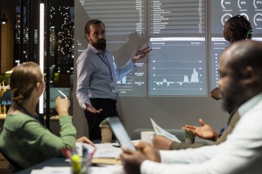 İş arkadaşları toplantı odasında grafik temsilleri ve paydaşlardan gelen geri bildirimleri inceledikten sonra gündemlerini gözden geçirmek için toplanıyor. Personel ve takım lideri bakış açılarını değiştiriyor..