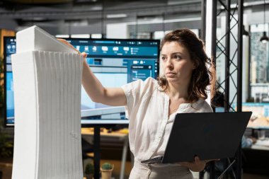 Emlak işindeki kadın müteahhit ofisteki 3D inşaat modellerini gözden geçiriyor. İkamet geliştirme projesi için şehir planlaması yapıyor. Kentsel gelişim için modern konut.