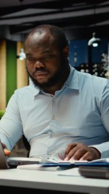 Dikey Video Güvenilir Erkek Çalışanı, gece geç saatlerde karanlık ofiste tek başına yeni bir proje üzerinde çalışıyor. Adam bilgisi ve aylık hedefleri kontrol ediyor. Kamera A.