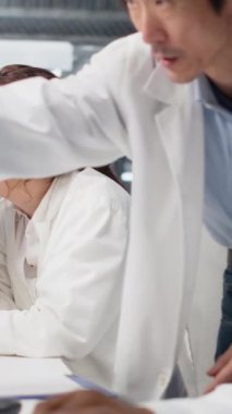 Bilgisayardaki moleküler modellere bakan bilim adamlarını denetleyen dikey video tanı laboratuvarı yöneticisi. Ekip lideri tıp laboratuarında biyomühendislik programı kullanan araştırmacıları denetliyor.