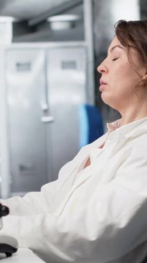 Dikey video yorgun laboratuvar bilim adamı gözlerini ovalıyor, genetik işaretleri PC kullanarak değerlendirmekten yoruldu. Yorgun uzman, bilgisayar masasındaki DNA iplikçikleri, iç çekmeler, kamera B...