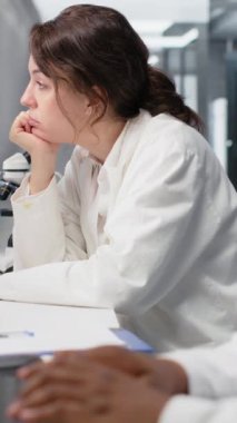 Dikey video laboratuvar yöneticisi bilgisayar üzerinde çalışan bilim adamlarını denetliyor, DNA verilerini işliyor. Laboratuvar başkanı ve çalışanları genetik analiz teşhislerine bakıyor, beyin fırtınası yapıyorlar.