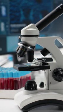 Biyoteknoloji laboratuvarındaki dikey video monitörü çalışma masasında moleküler modelleme ve mikroskop gösteriyor. Tıp laboratuarında biyomühendislik yazılımı DNA verileri gösteriyor ve...