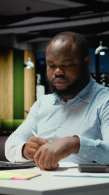 Dikey Siyah Adam, kağıt üzerinde temel fikirleri belgeliyor ve dizüstü bilgisayarda okuyor, geceleri görev planları yapıyor ve programlıyor. Hedefleri yansıtan bir sunum için el yazısıyla not alıyor