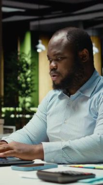 Dikey Afrikalı Amerikalı adam ofisteki gece lambasının ve dizüstü bilgisayarın farkına varıyor, yeni bir bakış açısı için strateji kuruyor ve işlerini bitiriyor. Gece geç saatlerde çalışıyor.