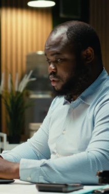 Dikey Video Kızgın Afro-Amerikalı adam sinirleniyor ve işlerini bitiremiyor, tükenmişlik ve zihinsel yorgunlukla uğraşıyor. Adam mesaiden sonra çalışıyor ve yorucu zorluklarla yüzleşiyor. Çok gerginim.