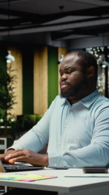 Dikey Video Kızgın Afro-Amerikalı adam sinirleniyor ve işlerini bitiremiyor, tükenmişlik ve zihinsel yorgunlukla uğraşıyor. Adam mesaiden sonra çalışıyor ve yorucu zorluklarla yüzleşiyor. Çok gerginim.