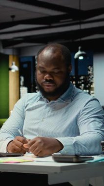 Dikey Video Siyah ofis çalışanı bir hata yaptıktan sonra bir kağıt parçasını yırtıyor, görevini öfkeyle yeniden başlatıyor ve sayfa sayfasını yırtıyor. Hoşnutsuz adam yazım hatası yazar.